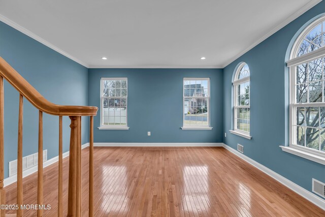 unfurnished room with visible vents, crown molding, baseboards, stairway, and hardwood / wood-style flooring