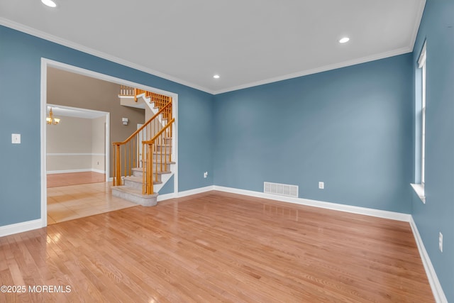 unfurnished room featuring stairs, crown molding, wood finished floors, and visible vents