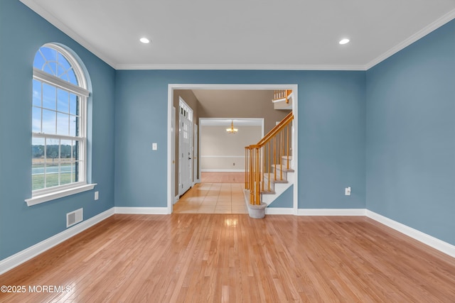 empty room featuring stairs, wood finished floors, visible vents, and baseboards