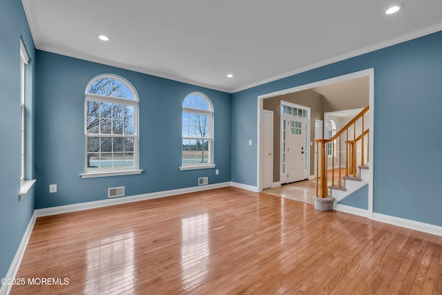 spare room with crown molding, stairs, baseboards, and hardwood / wood-style flooring