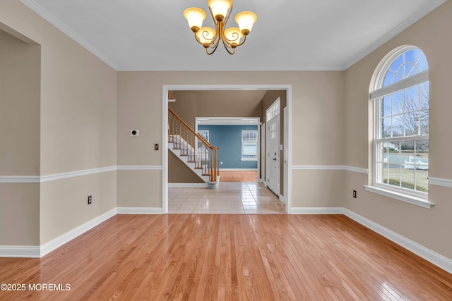 interior space featuring an inviting chandelier, light wood-style floors, baseboards, and ornamental molding