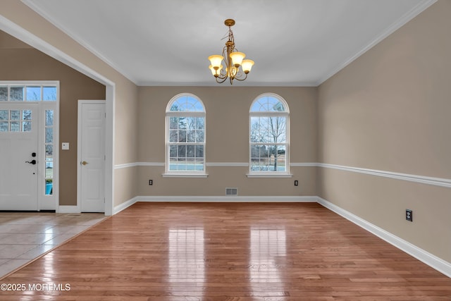 entryway featuring visible vents, wood-type flooring, a notable chandelier, and crown molding