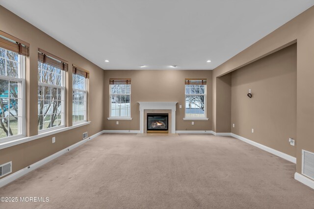 unfurnished living room with recessed lighting, a fireplace with flush hearth, light colored carpet, and baseboards