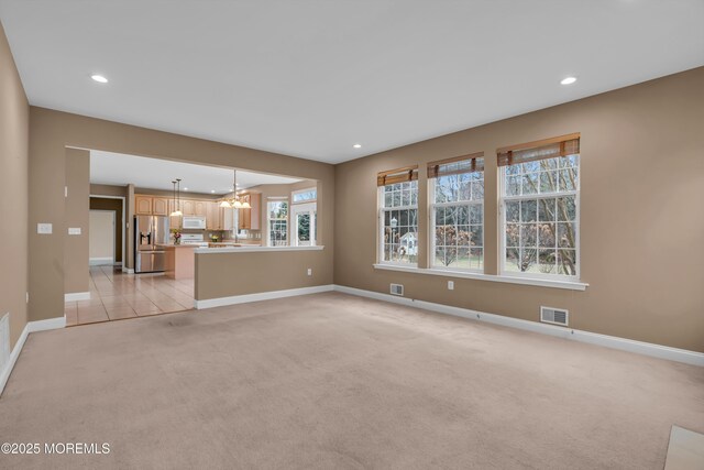 unfurnished living room featuring recessed lighting, light colored carpet, visible vents, and a chandelier