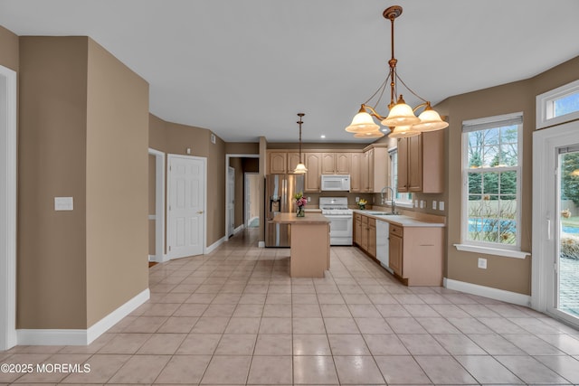 kitchen with a kitchen island, light countertops, light tile patterned floors, white appliances, and a sink