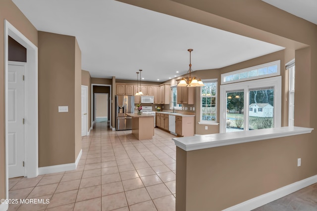 kitchen featuring a center island, light countertops, light tile patterned flooring, white appliances, and a sink