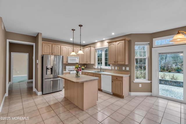 kitchen with light tile patterned floors, white appliances, light brown cabinetry, and light countertops