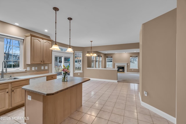 kitchen with dishwasher, light brown cabinets, a warm lit fireplace, and a sink