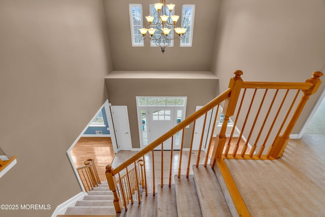 stairway with a notable chandelier, baseboards, and a towering ceiling