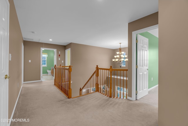 corridor with baseboards, an upstairs landing, a notable chandelier, and carpet floors