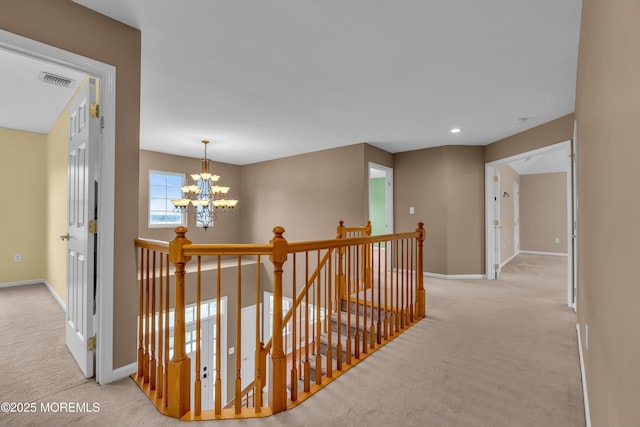 hall featuring an upstairs landing, visible vents, a notable chandelier, and carpet