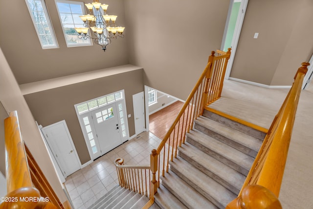 tiled entryway featuring visible vents, baseboards, a notable chandelier, and a towering ceiling