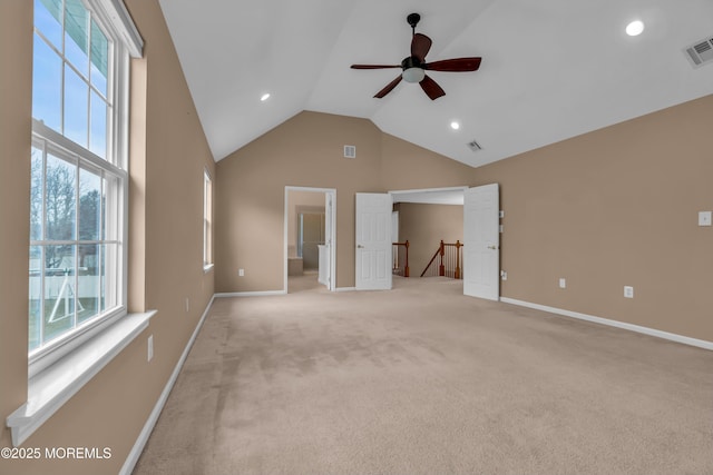 interior space featuring visible vents, baseboards, high vaulted ceiling, and light carpet