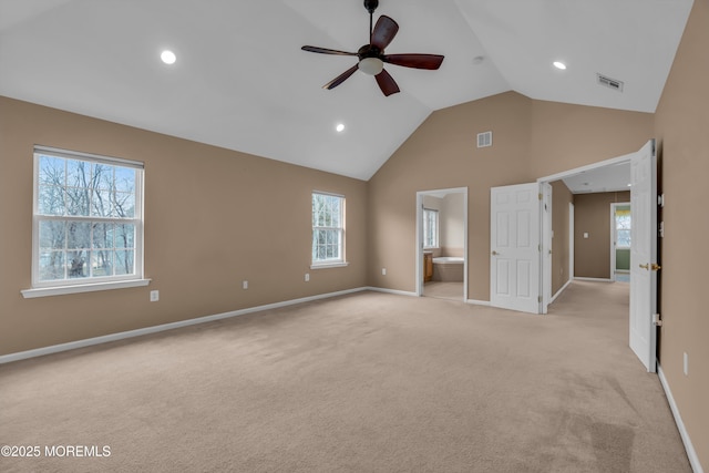 unfurnished bedroom featuring baseboards, visible vents, high vaulted ceiling, ensuite bath, and light carpet