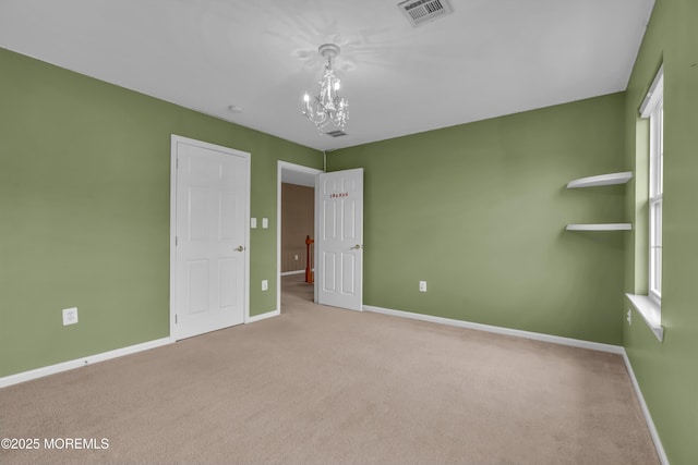 unfurnished bedroom with visible vents, baseboards, carpet floors, and an inviting chandelier