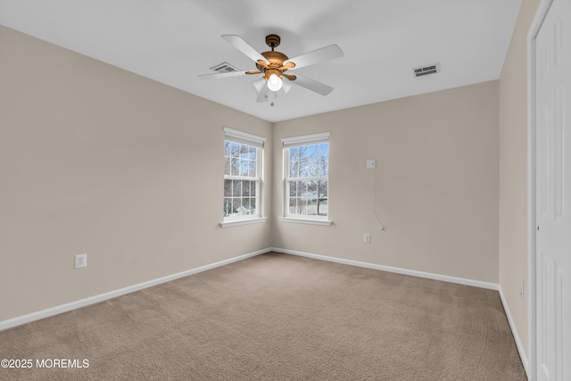 carpeted spare room featuring visible vents, a ceiling fan, and baseboards