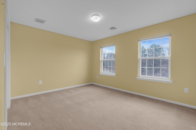 spare room featuring visible vents, baseboards, and light colored carpet