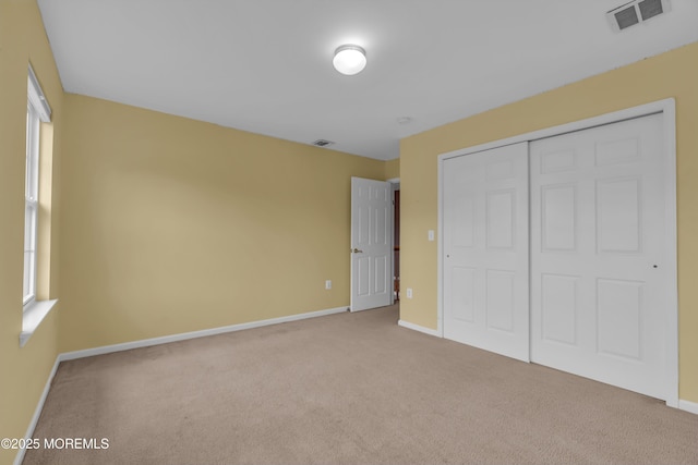 unfurnished bedroom with carpet flooring, visible vents, and a closet