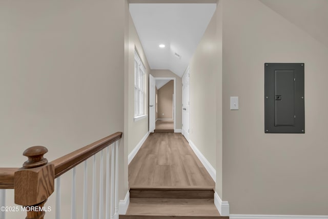 corridor featuring electric panel, lofted ceiling, baseboards, and wood finished floors