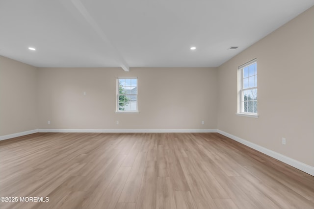 spare room featuring visible vents, baseboards, beamed ceiling, and light wood finished floors