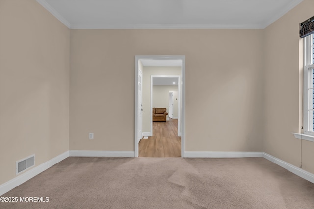 unfurnished room with crown molding, baseboards, visible vents, and carpet floors