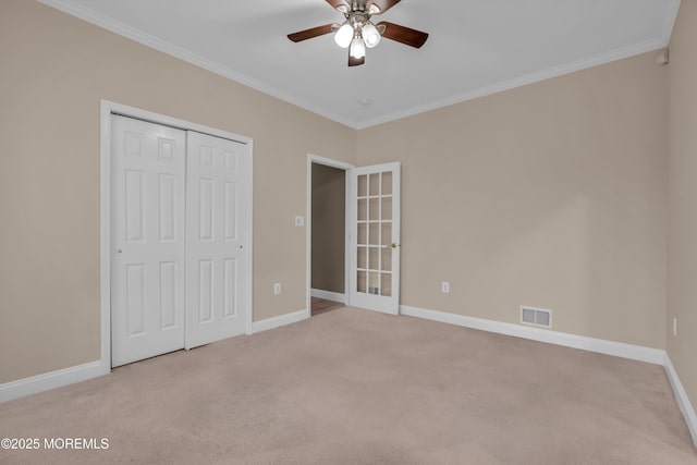 unfurnished bedroom featuring visible vents, baseboards, ornamental molding, carpet flooring, and a closet