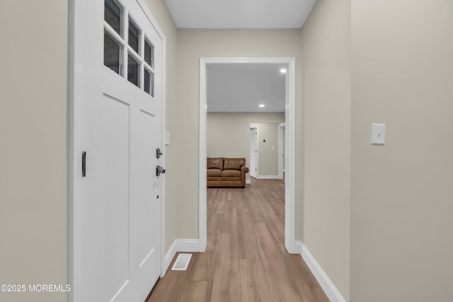 corridor featuring visible vents, light wood-type flooring, and baseboards