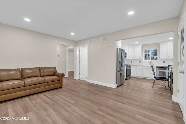 living room with recessed lighting, light wood-style floors, visible vents, and baseboards