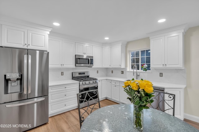 kitchen featuring light wood-type flooring, recessed lighting, stainless steel appliances, white cabinetry, and a sink