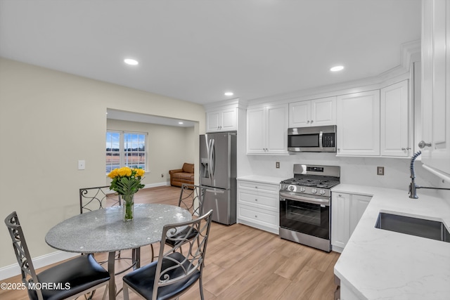 kitchen with recessed lighting, appliances with stainless steel finishes, light wood-style floors, white cabinetry, and a sink