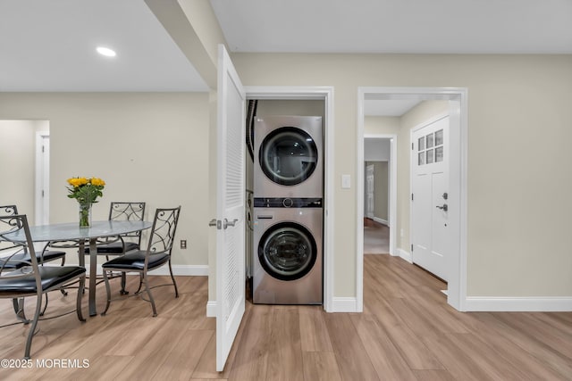 washroom with light wood-style flooring, stacked washing maching and dryer, recessed lighting, baseboards, and laundry area