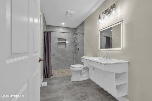 bathroom featuring a tile shower, visible vents, toilet, and vanity