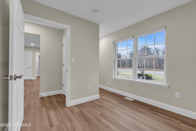 unfurnished room with visible vents, light wood-style floors, and baseboards