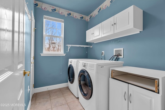 clothes washing area featuring separate washer and dryer, light tile patterned floors, cabinet space, and baseboards