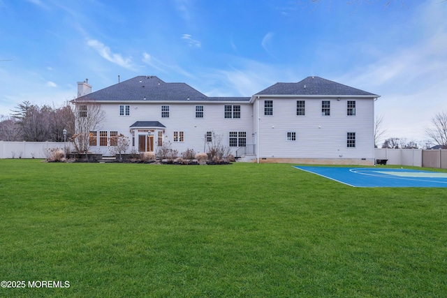 back of house with crawl space, a yard, fence, and basketball court