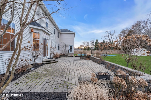 rear view of property with fence, entry steps, an outdoor fire pit, a lawn, and a patio