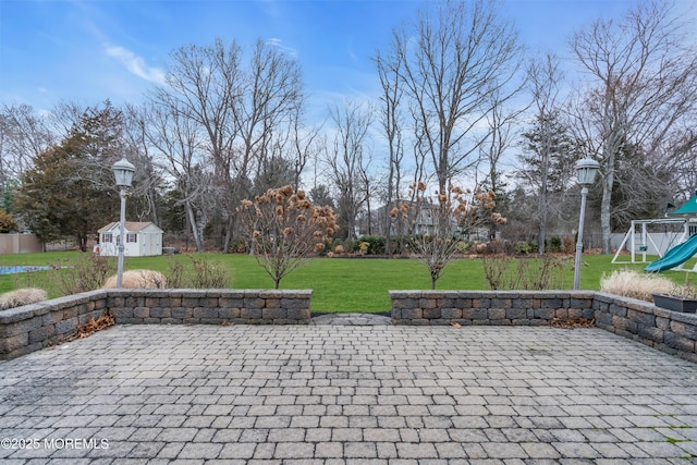 view of patio / terrace with a storage unit, an outdoor structure, and a playground