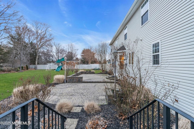 view of yard featuring a patio area, a playground, and a fenced backyard