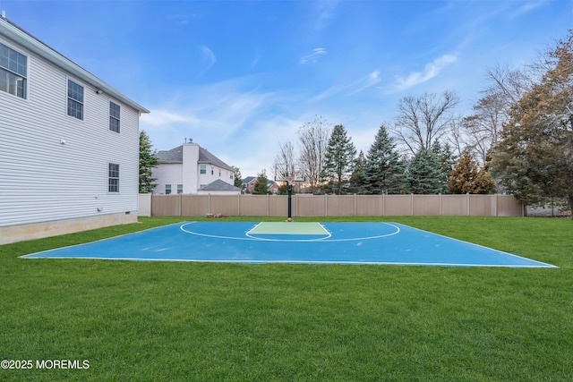 view of sport court featuring a yard, basketball hoop, and fence