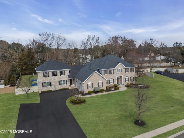 georgian-style home with a front lawn, fence, and driveway