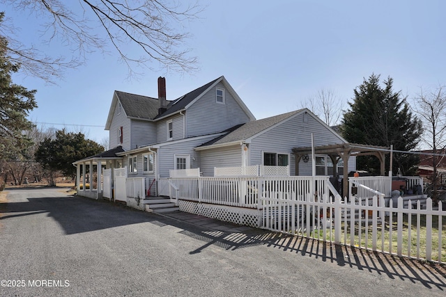 exterior space with fence, a wooden deck, roof with shingles, a chimney, and a pergola