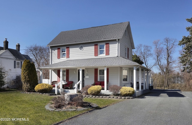 view of front of house featuring a porch, a front lawn, driveway, and a shingled roof