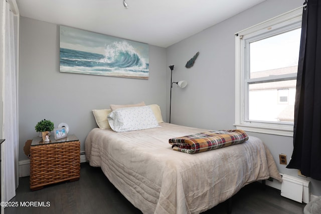 bedroom featuring a baseboard heating unit and wood finished floors