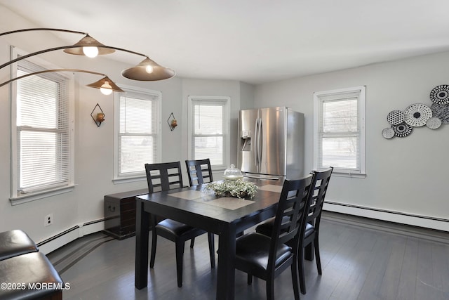 dining room featuring a baseboard radiator, plenty of natural light, and dark wood finished floors