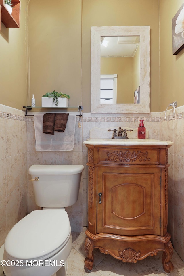 bathroom with a wainscoted wall, toilet, tile walls, and vanity