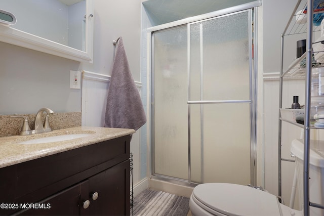 bathroom featuring toilet, a stall shower, and vanity