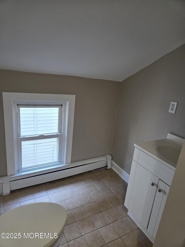 interior space with a sink, a baseboard radiator, baseboards, and tile patterned floors