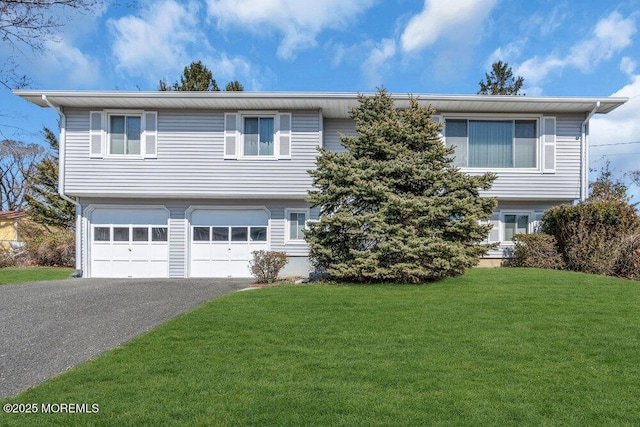 bi-level home featuring aphalt driveway, a garage, and a front lawn