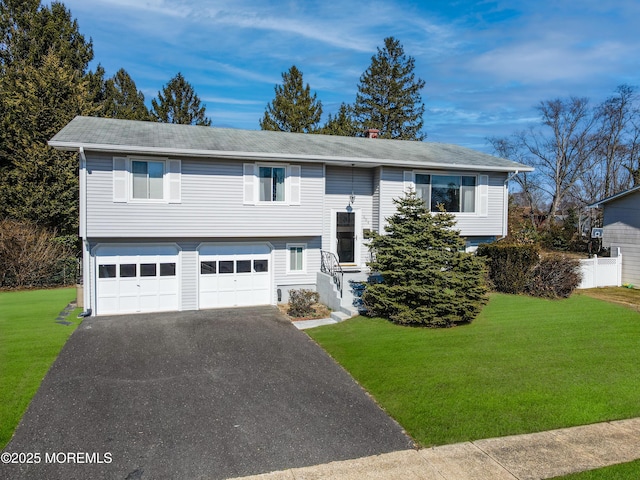 bi-level home with aphalt driveway, an attached garage, and a front lawn