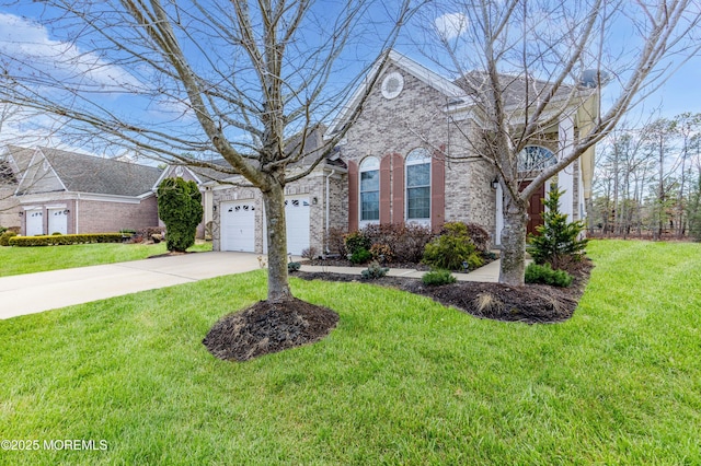 traditional-style home featuring brick siding, a garage, driveway, and a front yard